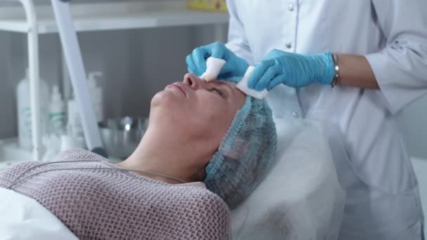 Kosmetologisk Behandling Kosmetolog Torka Ansiktet Sin Kvinnliga Klient Mittskott — Stockvideo
