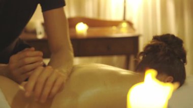 Masaj seansı. Kadın müşterisinin yağlı sırtına kollarıyla masaj yapıyor. Orta çekim