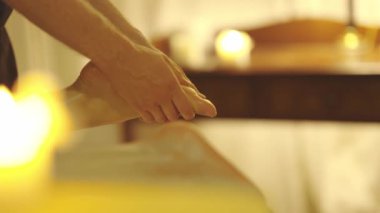 Sıcak ışık altında spa salonunda masaj. Terapist, kadın bir müşterinin ayağına masaj yapıyor. Orta çekim