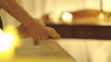 Sıcak mum ışığında spa salonunda masaj. Terapist, kadın bir müşterinin ayağına masaj yapıyor. Orta çekim