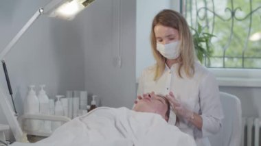 Bir dermatologla seans. Kadın müşteri için yüz masajı yapıyor. Orta çekim