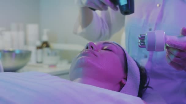 Bekerja Pada Kulit Wajah Pusat Kosmetologi Dalam Pencahayaan Ungu Ditengah — Stok Video