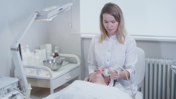 Terapeuta Massaggia Pelle Facciale Una Giovane Donna Usando Dispositivo Cosmetologico — Video Stock