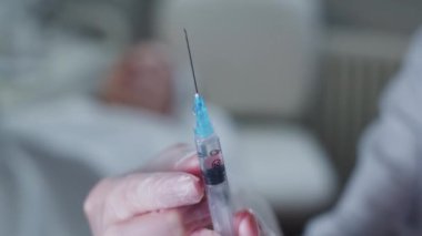 Usta kozmetik uzmanı şırıngadan fazla hava alıyor ve kanepeye müşterisine yaklaşıyor. Orta çekim