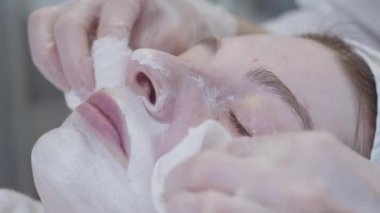 Güzellik uzmanı uygulamalı beyaz kil maskeden müşterilerin derisini siler. Orta çekim