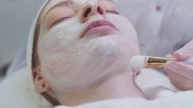 Kozmetik tedavisi. Müşterinin yüzüne ıslak beyaz maske takan usta. Orta çekim