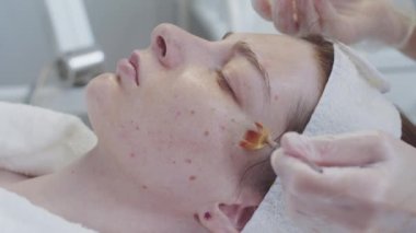 Güzellik uzmanı, müşterilerine nemlendirici sürmüş. Çilli ciltleri ince bir fırçayla. Orta çekim