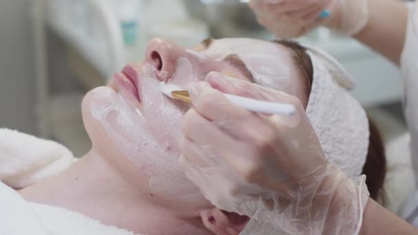 Leczenie Skóry Przez Kosmetologa Mistrza Smarowania Białej Maski Twarzy Klientki — Wideo stockowe