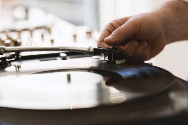 DJ 'in eli vinil plaktaki iğneyi ayarlıyor. Orta çekim