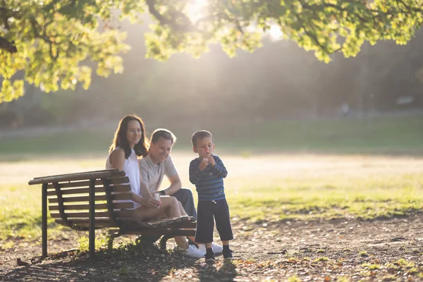 公园里可爱的白人家庭 一个吹泡泡肥皂泡的小男孩和他的父母看着他 — 图库照片