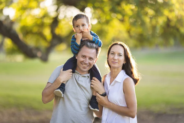 公园里可爱的白色微笑的家人 他的小儿子站在他的父亲和妻子的肩上 — 图库照片