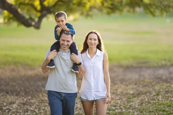 公园里可爱的白色微笑的家人 站在他父亲和妻子的肩上的小儿子 看着镜头 — 图库照片