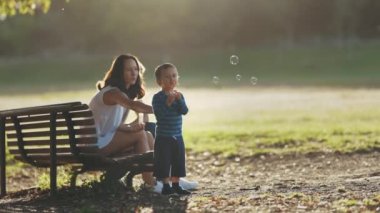 Aile parkta, sabun köpüğüyle oynayan küçük bir çocuk. Orta çekim