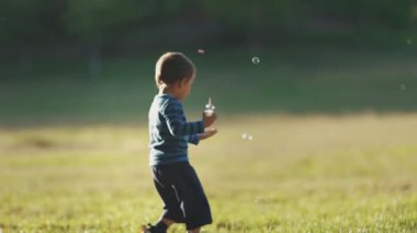 Sabun köpüğüyle oynayan küçük bir çocuk. Orta çekim