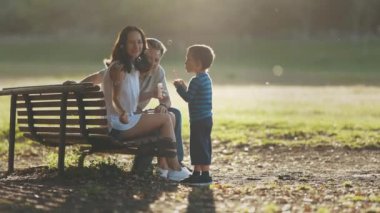 Aile parkta vakit geçiriyor. Sabun köpüğüyle oynayan tatlı bir çocuk. Orta çekim