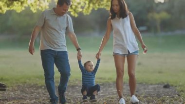 Parkta yürüyen sevimli genç bir aile. Orta çekim