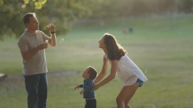Şirin, genç bir aile parkta vakit geçiriyor. Babası sabun köpüğü üflüyor. Orta çekim