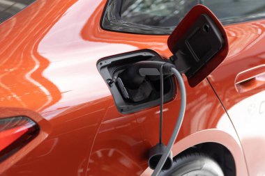 EV şarj istasyonunda turuncu elektro araba şarj ediliyor. Orta çekim