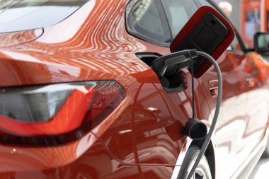 EV şarj istasyonunda turuncu elektro araba şarj edildi. Orta çekim