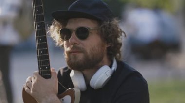 Kablosuz kulaklık takan ve gitar tutan bir adam. Orta çekim
