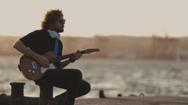 Rıhtımda gitar çalan bir adam. Orta çekim