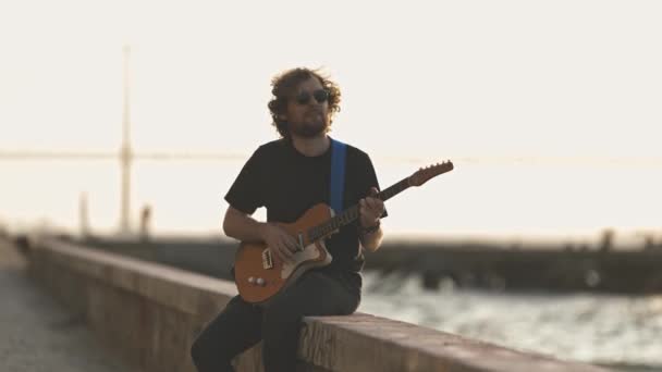 Ein Mann Sitzt Wasser Und Spielt Gitarre Frühen Sonnenuntergang Mittelschuss — Stockvideo