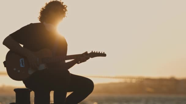 Ένας Άντρας Που Παίζει Κιθάρα Έξω Στο Φωτεινό Ηλιοβασίλεμα Μεσαίο — Αρχείο Βίντεο