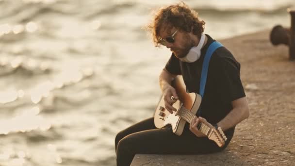 Homem Hipster Senta Dique Com Pernas Penduradas Água Toca Guitarra — Vídeo de Stock