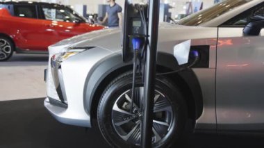 İçerideki şarj istasyonunda gümüş renkli elektro araba şarj ediliyor. Orta çekim