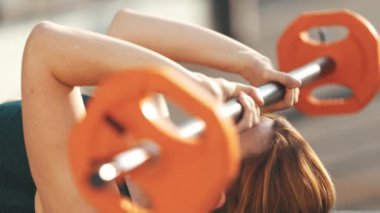 Yetişkin fitness kadını, yoga minderine uzanmış halterini kaldırarak ellerini çalıştırıyor. Orta çekim