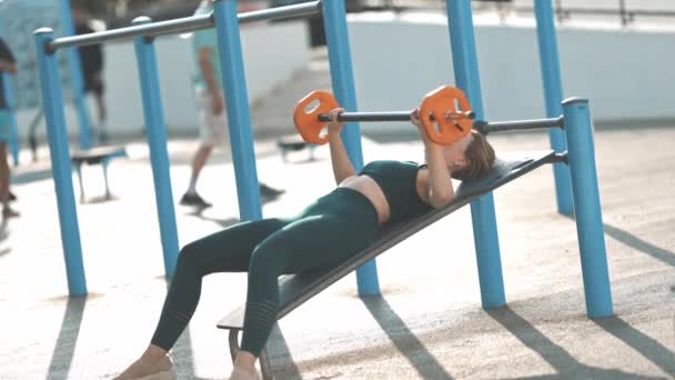 Dorosła Kobieta Fitness Trenuje Ręce Podnoszeniem Hantli Leżąc Symulatorze Sportowym — Wideo stockowe