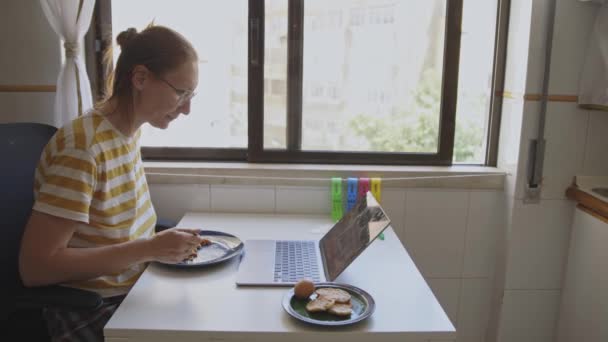 Взрослая Женщина Смотрит Свой Ноутбук Кухонным Столом Завтракает Средний Выстрел — стоковое видео