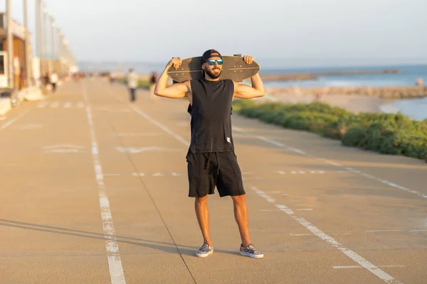 Een Glimlachende Man Weg Met Een Skateboard Zijn Schouders Tussenschot — Stockfoto