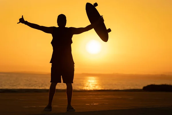 Силуэт Мужчины Показывающего Шаку Держащего Скейтборд Закате Средний Выстрел — стоковое фото