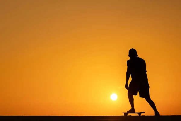 日落时一个人在滑板上滑冰的轮廓 — 图库照片