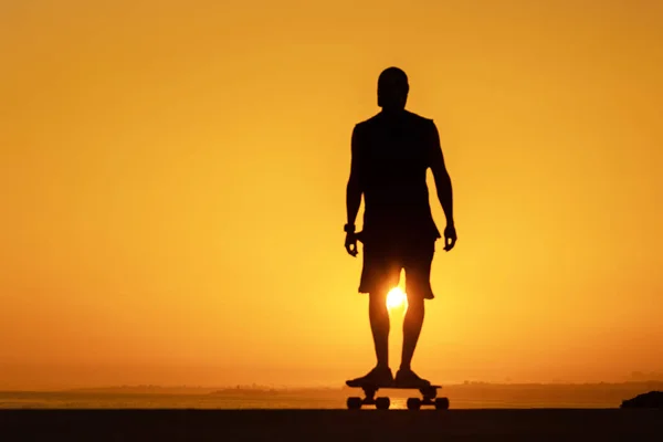 一个男人在日落时拿着一块滑板 展示了他的肖像 — 图库照片