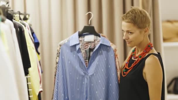 Взрослая Женщина Консультант Моде Подбирает Одежду Бутике Глядя Камеру Средний — стоковое видео