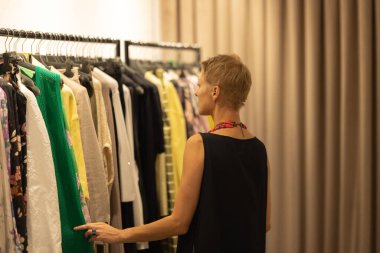 Yetişkin stili kadın moda danışmanı butikte kıyafetlere bakıyor. Orta çekim
