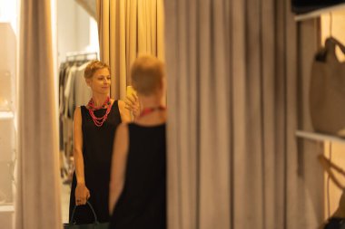 Yetişkin stili kadın moda danışmanı butiğin aynasında kendi fotoğrafını çekiyor. Orta çekim