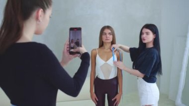 Bir kadın telefon kamerasından zayıf bir modelin vücut ölçülerini alıyor. Orta çekim