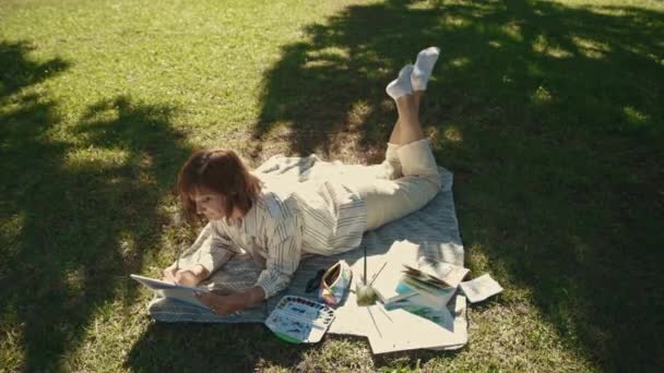 Uma Mulher Adulta Inspirada Deitada Cobertor Parque Florescente Desenhando Seu — Vídeo de Stock