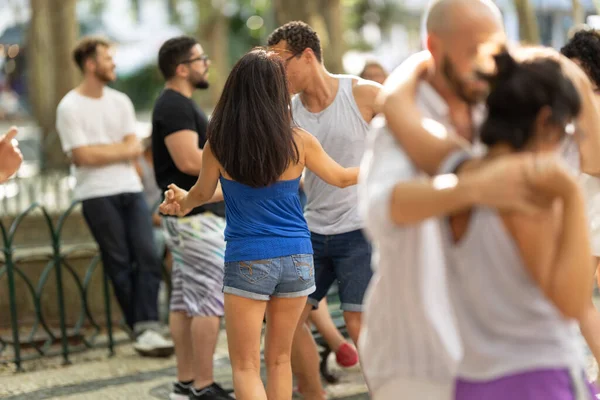 Sokakta insanların etrafında dans eden genç bir çift. Orta çekim