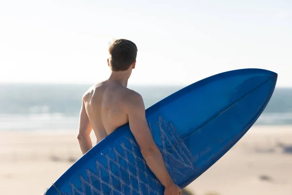 Чоловік Голим Торсом Стоїть Пляжі Тримає Блакитну Дошку Серфінгу Вид — стокове фото