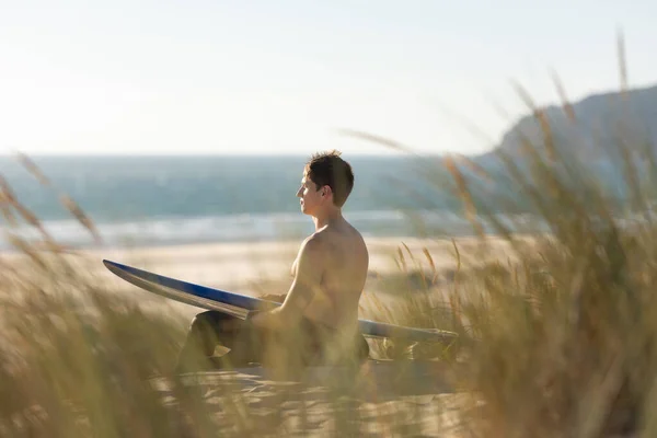 Hombre Sentado Playa Sosteniendo Una Tabla Surf Azul Mid Shot — Foto de Stock