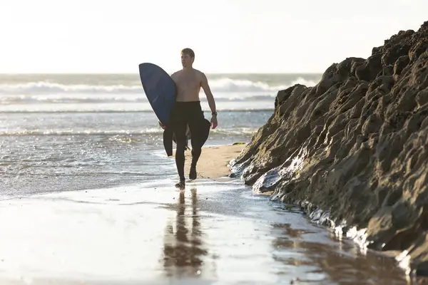Hombre Con Torso Desnudo Caminando Por Playa Sosteniendo Una Tabla — Foto de Stock