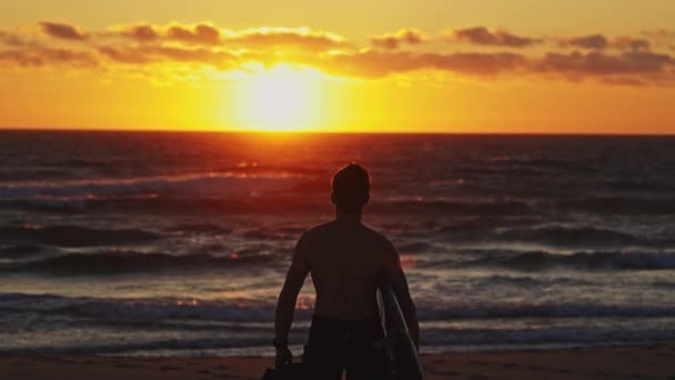 Silhueta Surfista Homem Caminhando Para Oceano Pôr Sol Laranja Brilhante — Vídeo de Stock