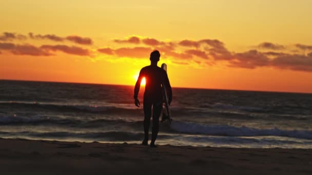 Silhouette Egy Felnőtt Férfi Szörfös Sétál Óceánhoz Fényes Narancssárga Naplemente — Stock videók