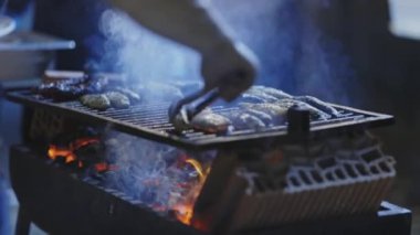 Bir insan ızgaradan kızarmış balık çıkarır. Orta çekim