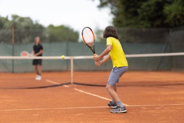 İki çocuk arkadaşça tenis oynuyor. Orta çekim
