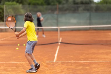 Sahada dostça tenis oynayan iki çocuk. Orta çekim